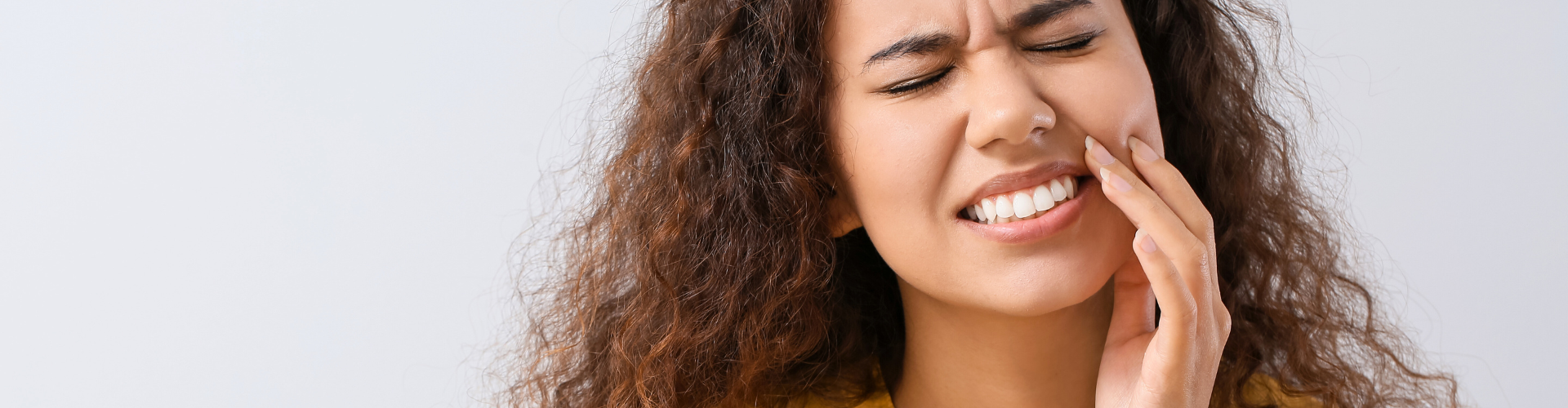 Woman holding her cheek in pain.